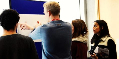 artists looking at a piece of work on a blue propped up false wall.