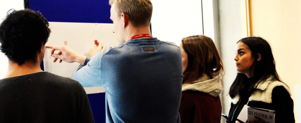 artists looking at a piece of work on a blue propped up false wall.