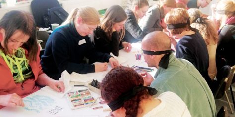 people blindfolded, drawing at a table